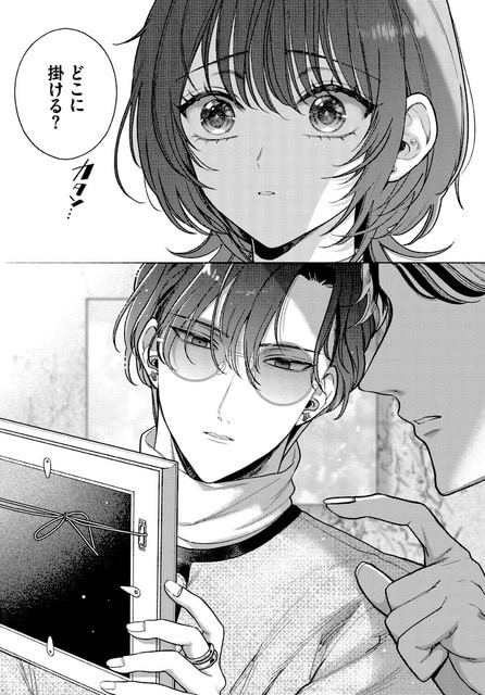 丸メガネの男性が額縁を両手で持ちながら、近くに立つ男性と展示場所について会話している